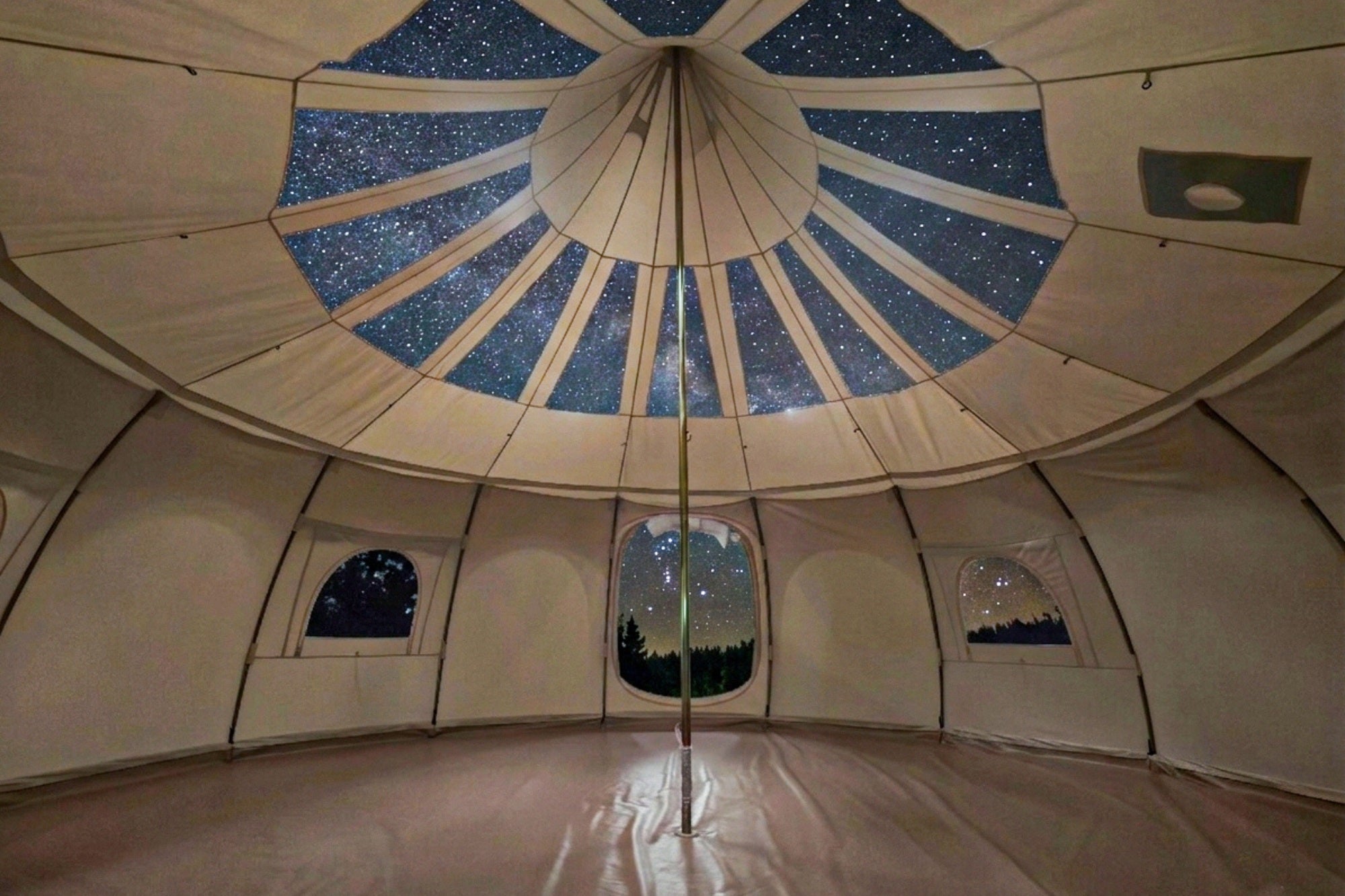 20ft Better Bell tent interior with panoramic stargazing roof panels, central pole, and night sky visible through windows